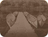 Large canoes moored along a floating dock on a calm lake, with autumn forest reflected in the water