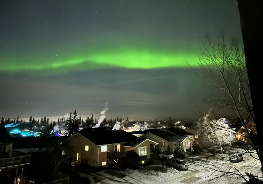 Green northern lights over a snow-covered Fort McMurray, Alberta neighbourhood at night